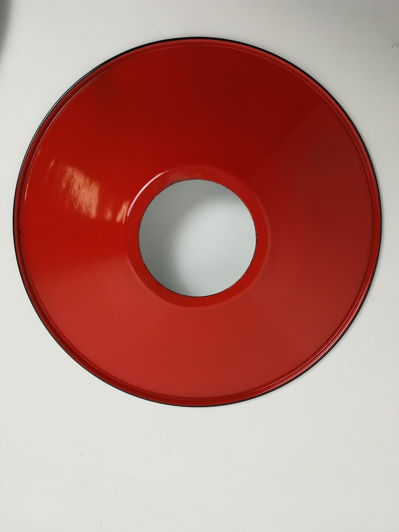 May include: A red metal lampshade with a black rim and a circular opening in the center.