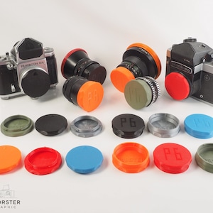 May include: A collection of camera lens caps in various colors, including red, orange, green, blue, and gray. The caps are made of plastic and have different markings, including "P6" and "MASTER".