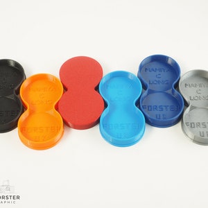 May include: Five 3D printed camera lens holders in different colours: black, orange, red, blue, and grey. Each holder has two compartments and is labelled "Mamiya C Long" and "Forster UK".