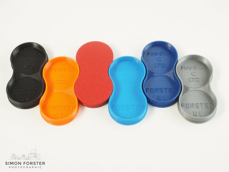 May include: Five different coloured plastic film canisters for a Mamiya C camera. The canisters are labelled "Mamiya C STD" and "FORSTER UK".