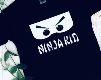 May include: Black t-shirt with a white graphic of a ninja mask and the text "Ninja Kid".