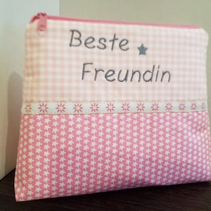 Könnte beinhalten: Rosa-weiße Stofftasche mit Reißverschluss. Der obere Teil hat ein Vichy-Muster, der untere Teil ein Blumenmuster. Die Worte "Beste Freundin" sind grau gestickt, mit einem kleinen Stern.
