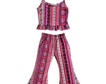 May include: A two-piece set featuring a patterned crop top with spaghetti straps and a ruffled hem, paired with matching flared pants. The set showcases a vibrant design in shades of red, purple, and white, with intricate geometric and floral patterns.