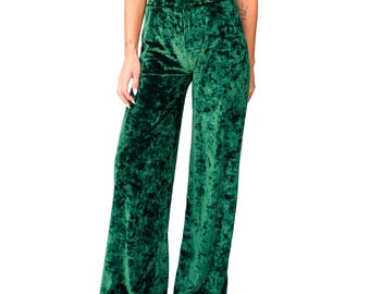 May include: Emerald green velvet palazzo pants. These high-waisted pants have a wide leg design and a soft, textured appearance. The pants are made of a crushed velvet material.