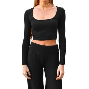 May include: Black long-sleeve crop top with a scoop neckline and matching black high-waisted pants. The top has a fitted silhouette, and the pants have a wide leg design. The outfit is made of a soft, stretchy material.