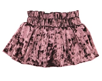 May include: A dusty rose velvet skirt with a gathered waistband. The skirt has a flared silhouette and a soft, textured appearance. The fabric has dark brown mottled accents throughout.