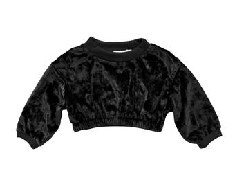 May include: Black velvet cropped sweatshirt with a crew neck and long, slightly puffed sleeves. The bottom hem is elasticized. The fabric has a soft, textured appearance.