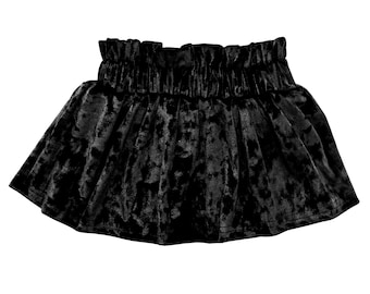 May include: A black velvet skirt with a high, gathered waistband. The skirt has a flared silhouette and a soft, textured appearance. The fabric has a subtle sheen, adding to its luxurious look. This skirt is suitable for various occasions.