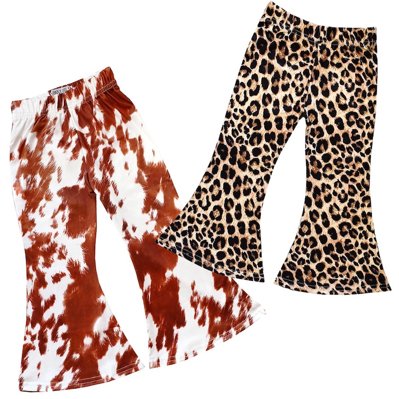 May include: Two pairs of girls' bell bottom pants. One pair is brown and white cow print and the other is brown and black leopard print.