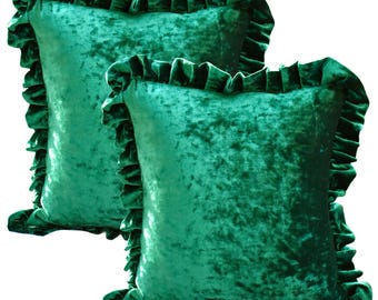 May include: Two emerald green velvet throw pillows with ruffled edges. The pillows have a soft, crushed velvet texture and a square shape. The ruffled trim adds a decorative touch to the pillows, which are suitable for home decor.