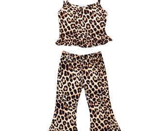 May include: A two-piece leopard print outfit. The top is a camisole with thin straps and a ruffled hem. The pants are flared at the bottom. The outfit is in shades of brown and black.