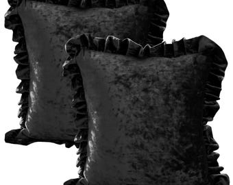 May include: Two black velvet throw pillows with ruffled edges. The pillows have a square shape and a soft, textured appearance. The ruffled trim adds a decorative element to the pillows, enhancing their visual appeal. These pillows are suitable for home decor.