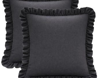 May include: Two square charcoal gray throw pillows with ruffled edges. The pillows have a solid color design and a textured appearance. The ruffled edges add a decorative element to the pillows. These pillows are suitable for home decor.