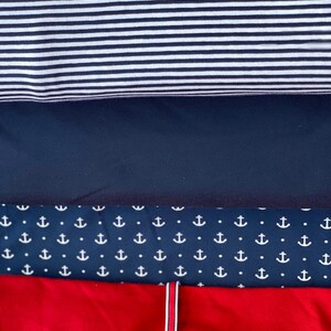 May include: Four fabric swatches, stacked on top of each other. The top swatch is white and black striped, the second swatch is dark blue, the third swatch is dark blue with a white anchor pattern, and the bottom swatch is red.