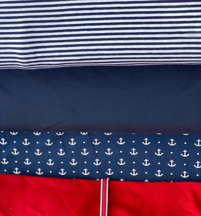 May include: Four fabric swatches, stacked on top of each other. The top swatch is white and black striped, the second swatch is dark blue, the third swatch is dark blue with a white anchor pattern, and the bottom swatch is red.