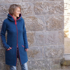 May include: A long, blue hooded jacket with red zipper and trim. The jacket has two pockets and is made of a soft, textured fabric.