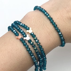 May include: Three teal blue crystal bracelets with gold and silver Mickey Mouse charms.