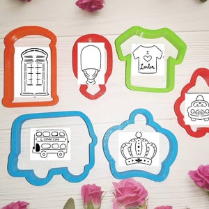 May include: Set of seven cookie cutters in various shapes and sizes, including a phone booth, a crown, a bus, a t-shirt, a car, and two guards. The cutters are made of red, green, and blue plastic.