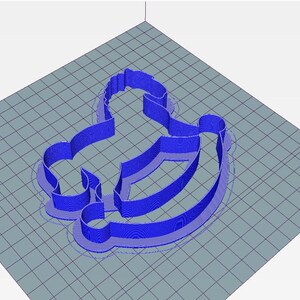 May include: A blue 3D-printed cookie cutter in the shape of a rocking horse. The cutter is on a grey surface with a grid pattern. The rocking horse design is detailed and has a smooth, rounded shape.