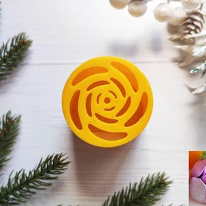 May include: Yellow round soap dish with a floral design. The soap dish is made of silicone and has a swirl pattern.
