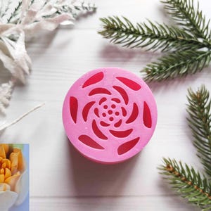 May include: Pink silicone mold shaped like a rose with a swirl pattern. The mold has a circular shape and is designed for baking or crafting.
