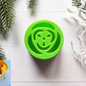 May include: A green plastic mold for making flower-shaped cookies or fondant decorations. The mold features a detailed design of a flower with a central circle and petals.