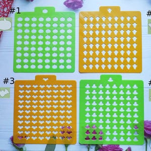May include: Four green and orange plastic stencils with different Halloween-themed designs. The stencils are numbered 1 through 4. Stencil #1 has a pumpkin design, #2 has a ghost design, #3 has a bat design, and #4 has a witch hat design.