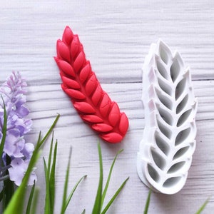 May include: A red silicone mould of a wheat stalk, and a white plastic mould of a wheat stalk.