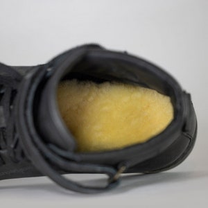 Peut inclure: Chaussures montantes en cuir noir avec une doublure en polaire douce de couleur beige clair.