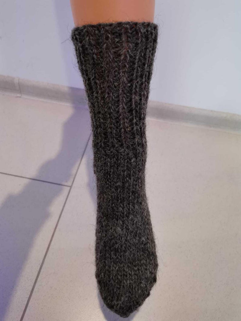 K&ouml;nnte beinhalten: Ein Paar dunkelgraue Wollsocken mit einem gerippten Strickmuster.