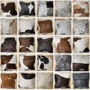 Puede incluir: Veinticuatro almohadas cuadradas con una variedad de patrones de piel de vaca, incluyendo blanco y negro, marrón y blanco, y marrón y negro. Las almohadas están dispuestas en un patrón de cuadrícula. La última almohada es una almohada con cremallera negra sólida.