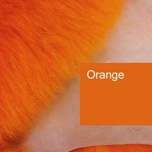 Könnte beinhalten: Nahaufnahme eines leuchtend orangen, flauschigen Stoffes. Der Stoff ist weich und flauschig. Das Wort "Orange" ist in Weiß auf einem einfarbigen orangen Hintergrund gedruckt.