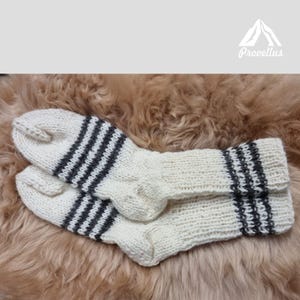 K&ouml;nnte beinhalten: Ein Paar wei&szlig;e Stricksocken mit schwarzen Streifen. Die Socken sind aus Wolle und perfekt, um Ihre F&uuml;&szlig;e im Winter warm zu halten.