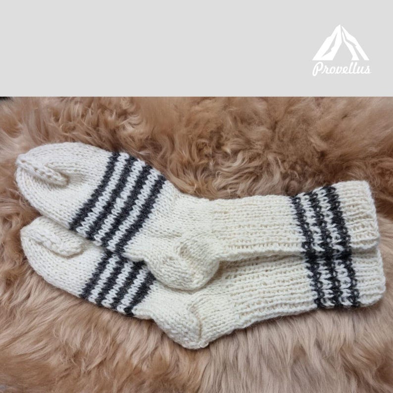 K&ouml;nnte beinhalten: Ein Paar wei&szlig;e Stricksocken mit schwarzen Streifen. Die Socken sind aus Wolle und perfekt, um Ihre F&uuml;&szlig;e im Winter warm zu halten.