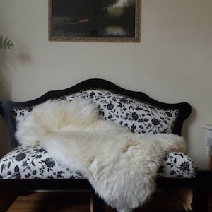 May include: A black and white floral patterned couch with a white sheepskin throw draped over it.
