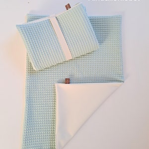 Könnte beinhalten: Eine hellblaue Waffel-Babydecke mit einem passenden, kleineren hellblauen Waffel-Spucktuch. Beide Artikel haben eine weiße Rückseite und ein braunes Etikett mit dem Text "Kindallerliebst".