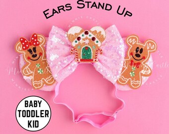 May include: Pink sparkly headband with gingerbread house and gingerbread man character ears. The headband says "EARS STAND UP" and "BABY TODDLER KID".