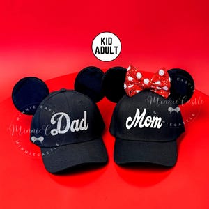 May include: Black baseball caps with the words "Dad" and "Mom" in white script. The "Mom" cap has a red and white polka dot bow. The image also includes black mouse ears and the text "Kid Adult".