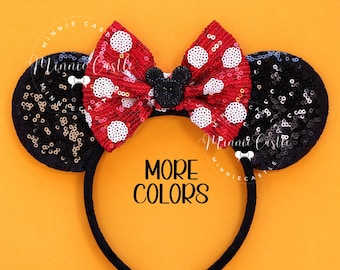 May include: Black headband with black and gold sequined Minnie Mouse ears and a red and white polka dot bow with a black Mickey Mouse head in the center. The text "MORE COLORS" is printed below the bow.