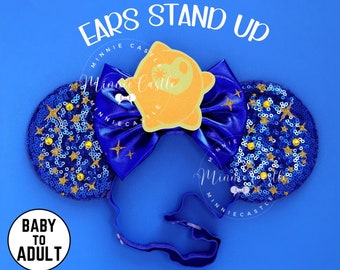May include: Blue and gold sequined Minnie Mouse ears with a yellow star-shaped bow and the text "EARS STAND UP" on a blue background.