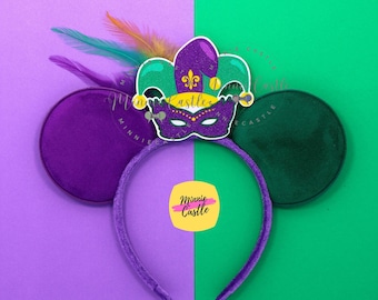 Könnte beinhalten: Ein lila Stirnband mit daran befestigten lila und grünen Ohren und einer Maske im Mardi-Gras-Stil. Die Maske ist lila mit grünen und goldenen Akzenten und mit Federn verziert. Der Hintergrund ist zwischen Lila und Grün geteilt.