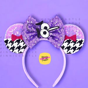 May include: A purple sequined bow headband with mouse ears. The ears are lavender with sequins and a black and white houndstooth pattern. A cartoon character is on the bow. A small pink bow is on each ear. The headband is lavender.