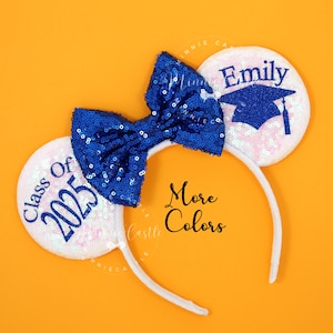 May include: White headband with blue sequin bow and two white ears. One ear has the text "Class of 2025" and the other ear has the text "Emily" with a blue graduation cap.