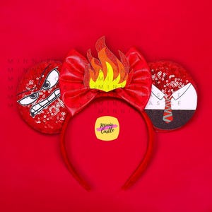 May include: Red and black mouse ears with a red bow, a flame design, and a cartoon face with an angry expression. The ears are decorated with sequins. The text "Minnie Castle" is on a yellow sticker.