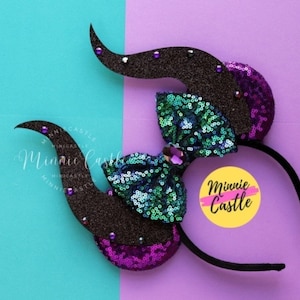 May include: Black headband with purple and green sequined ears and a large green bow with a jewel in the center. The headband has the text "Minnie Castle" on a yellow circle.