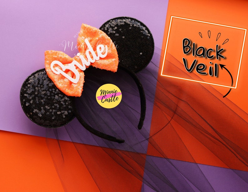 May include: Black and orange Minnie Mouse ears with a white "Bride" bow and a black tulle veil. The ears are decorated with black sequins. The veil is labeled "Black Veil".