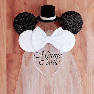 May include: White bridal Minnie Mouse ears with a black top hat, a white bow, and a white tulle veil. The ears are decorated with sequins. The headband says "Minnie Castle".