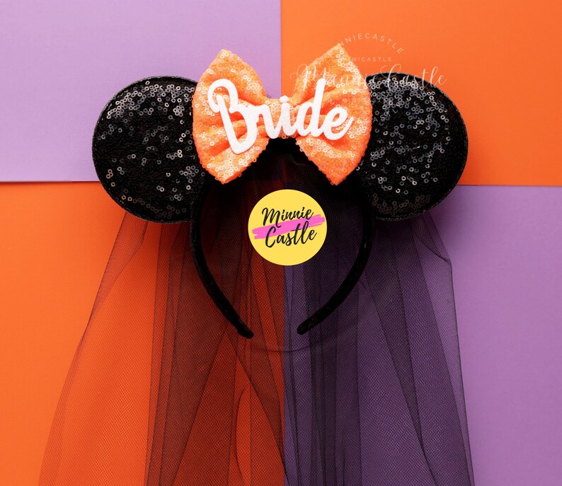 May include: Black and orange Minnie Mouse ears with a veil and a white bow that says "Bride".