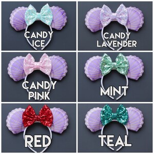 May include: A collection of six headbands with seashell-shaped ears in lavender, each featuring a sequined bow in various colors: Candy Ice, Candy Lavender, Candy Pink, Mint, Red, and Teal. The text on each headband indicates the color.