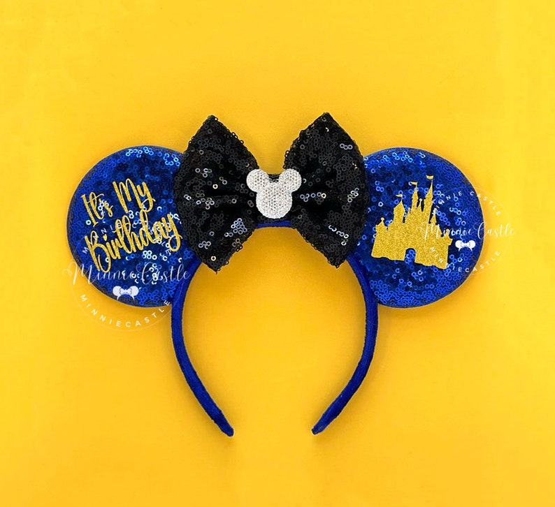 May include: Blue and black sequined Minnie Mouse ears with a gold castle and the text "It's My Birthday" in gold lettering.
